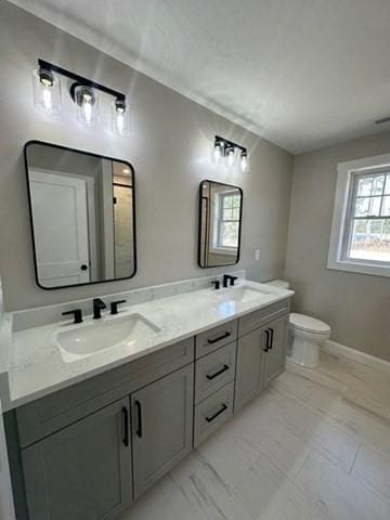 full bathroom with double vanity, toilet, baseboards, and a sink