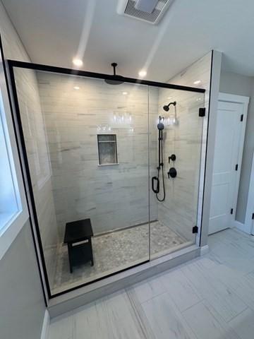 bathroom with baseboards, visible vents, and a stall shower