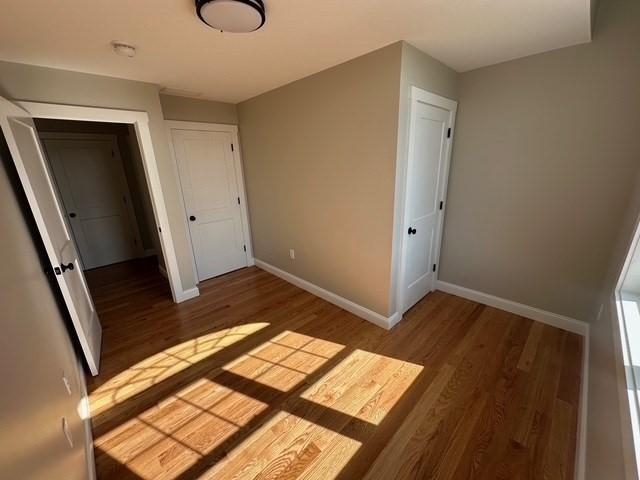 unfurnished bedroom with baseboards, wood finished floors, and a closet
