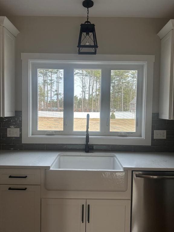 kitchen featuring white cabinets, stainless steel dishwasher, light countertops, and a sink