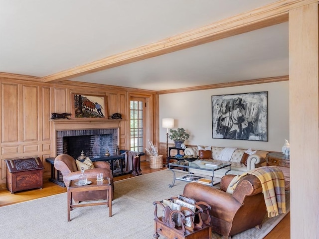 living room with a brick fireplace, crown molding, beam ceiling, and light hardwood / wood-style flooring