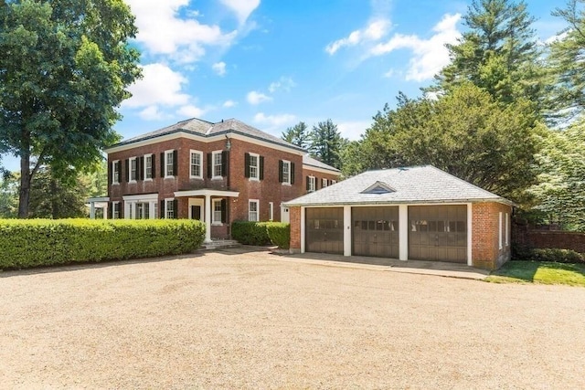 colonial home featuring a garage and an outbuilding