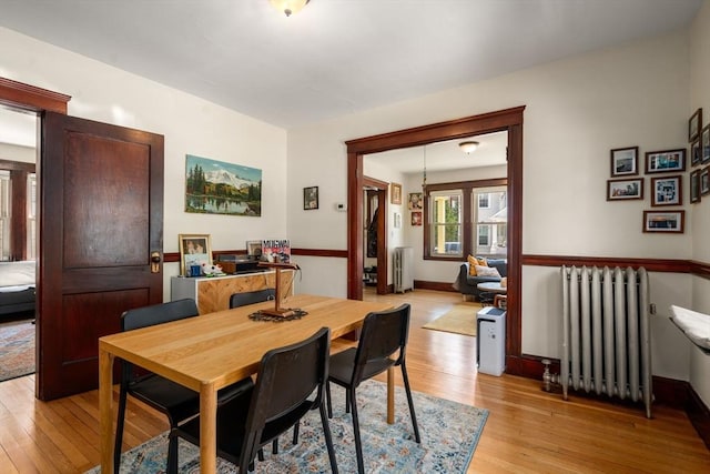 dining room with radiator heating unit, light wood-style flooring, and baseboards