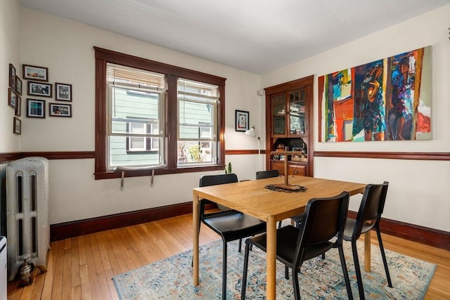 dining room with radiator, light wood-type flooring, and baseboards