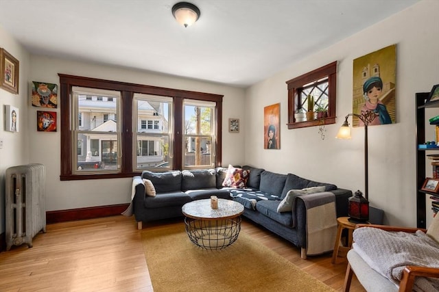 living area with radiator heating unit, light wood-style floors, and baseboards