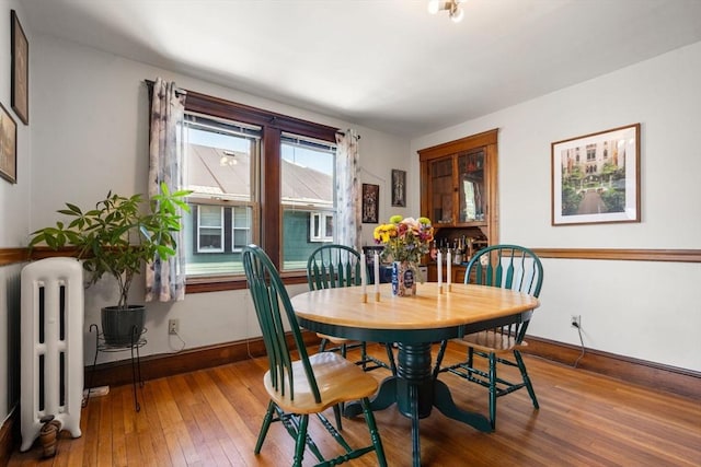 dining space featuring radiator, hardwood / wood-style flooring, and baseboards