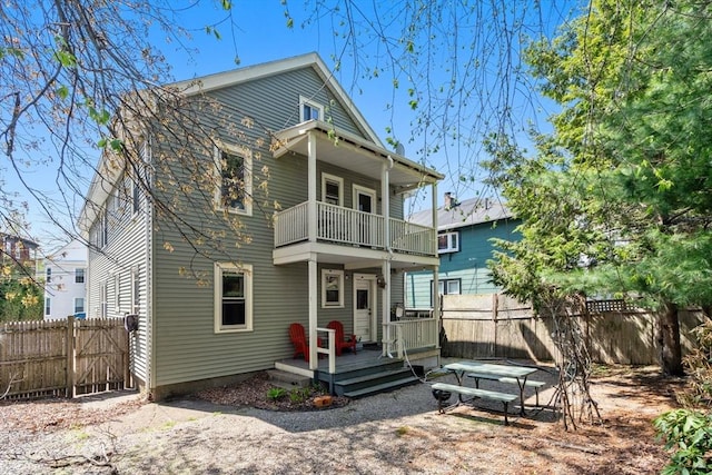 back of property featuring a balcony, fence, and a wooden deck