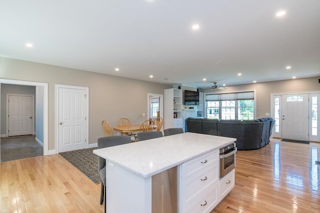 3 Ethan Cir, South Hadley, MA 01075 - kitchen featuring oven, white cabinetry, open floor plan, a center island, and light wood-style flooring