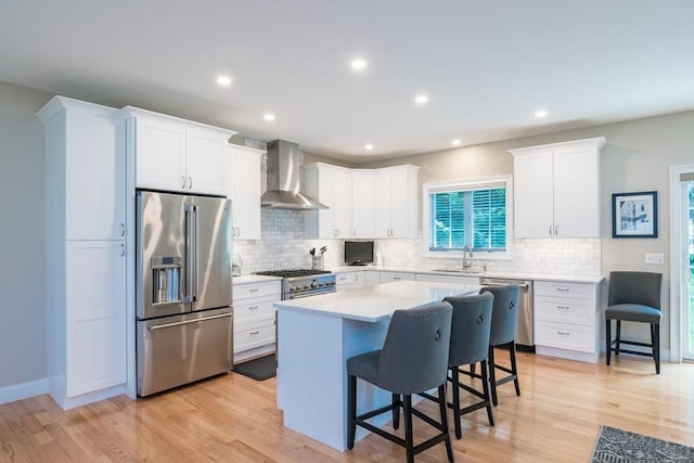 3 Ethan Cir, South Hadley, MA 01075 - kitchen featuring high end appliances, wall chimney range hood, a kitchen bar, a center island, and light wood finished floors