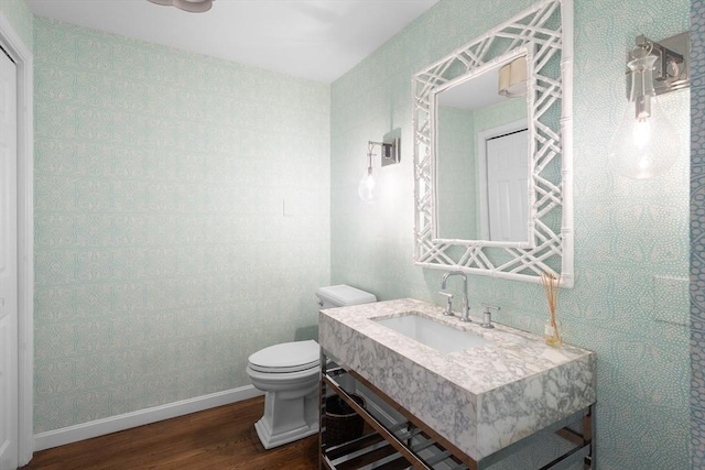 bathroom with baseboards, toilet, wood finished floors, and vanity