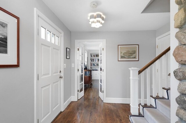 entryway with baseboards, a notable chandelier, wood finished floors, and stairs