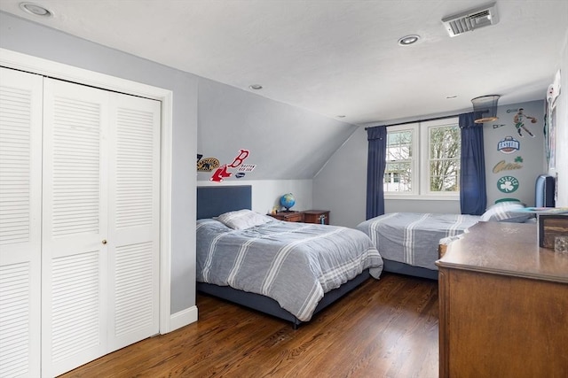 bedroom featuring visible vents, lofted ceiling, dark wood-type flooring, and a closet