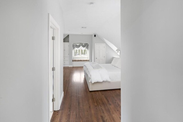 unfurnished bedroom with vaulted ceiling and wood finished floors