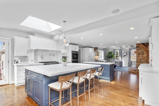 kitchen featuring a skylight, white cabinets, and a kitchen island