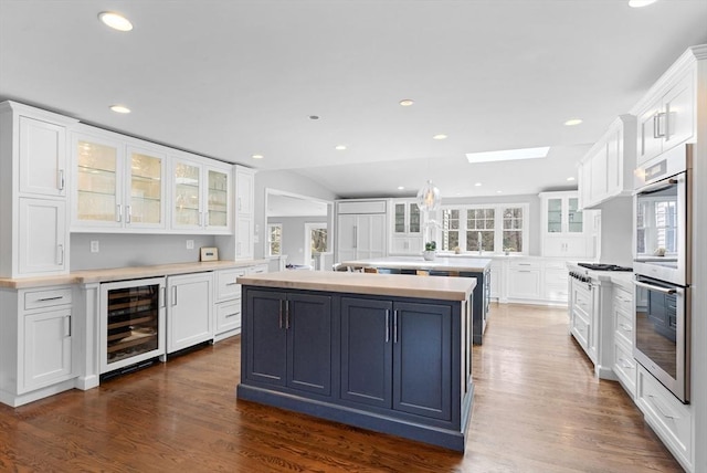 kitchen with a center island, wine cooler, a skylight, white cabinets, and a healthy amount of sunlight