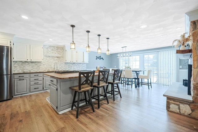 kitchen with wood counters, a breakfast bar area, freestanding refrigerator, a center island, and pendant lighting