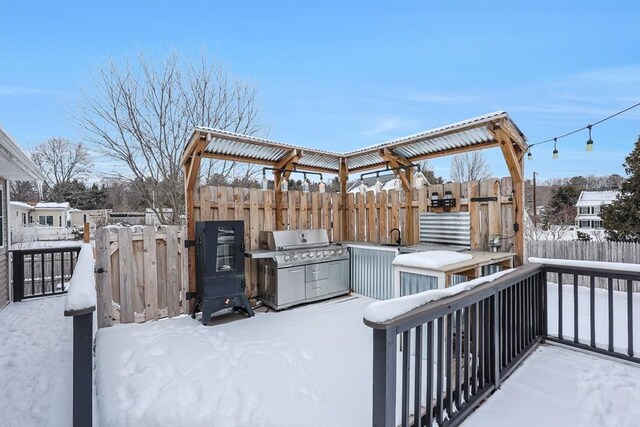 snow covered patio featuring a grill and fence