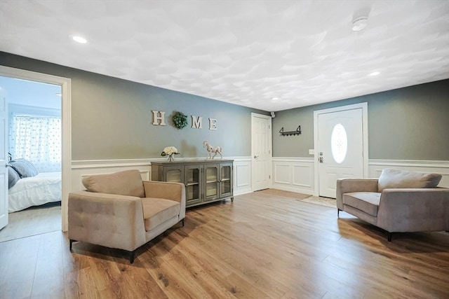 living area with recessed lighting, a wainscoted wall, a decorative wall, and wood finished floors