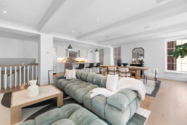 living room featuring crown molding, beamed ceiling, and light wood-type flooring