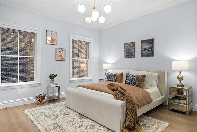 bedroom with hardwood / wood-style floors, ornamental molding, and a notable chandelier