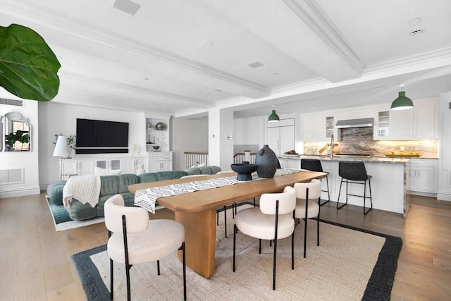 dining space featuring beam ceiling, light wood-type flooring, and ornamental molding