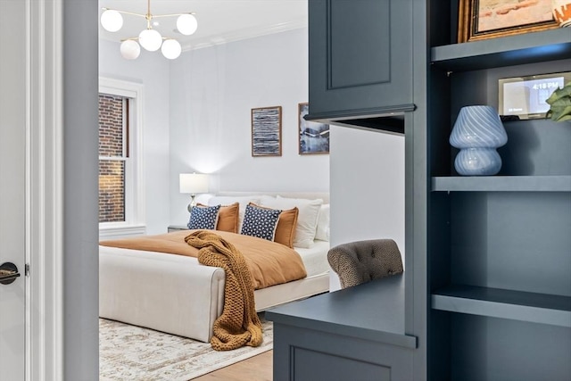 bedroom featuring a notable chandelier, crown molding, and light hardwood / wood-style flooring