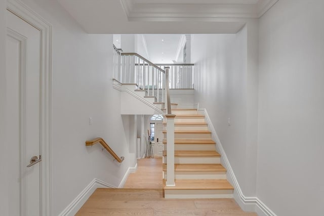 stairway featuring wood-type flooring and crown molding