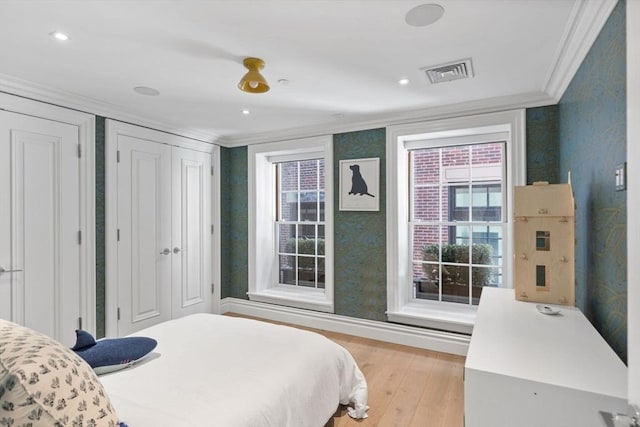 bedroom featuring ornamental molding and light hardwood / wood-style flooring