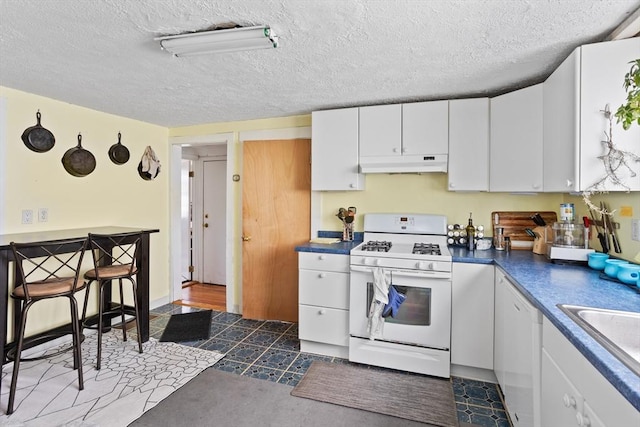 28 Gardner St, Arlington, MA 02474 - kitchen featuring white gas range, under cabinet range hood, white cabinets, a sink, and dark countertops