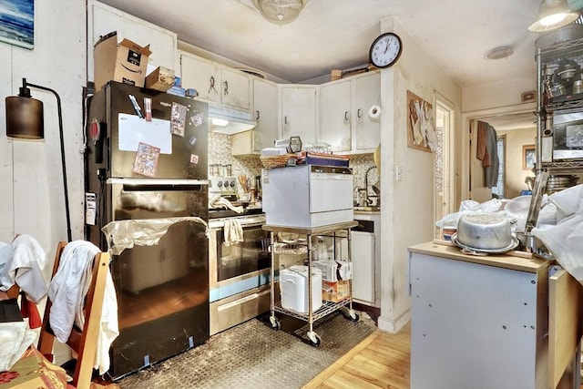 kitchen featuring white cabinetry, black fridge, stainless steel electric range oven, and light hardwood / wood-style floors