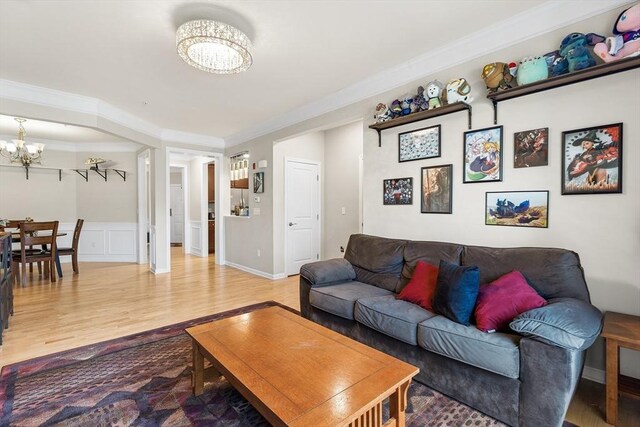 living room with hardwood / wood-style floors, ornamental molding, and a chandelier