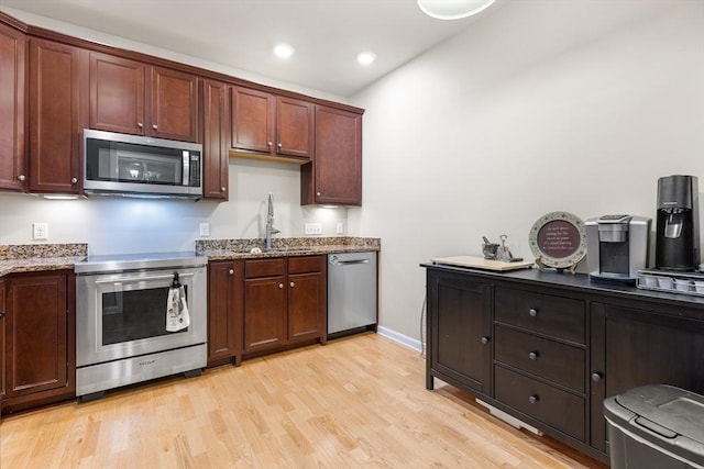 kitchen with light hardwood / wood-style floors, sink, light stone countertops, and stainless steel appliances