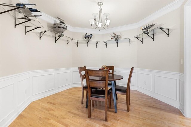 dining space with light wood-type flooring, crown molding, and a chandelier