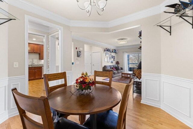 dining area with sink, light wood-type flooring, and ornamental molding
