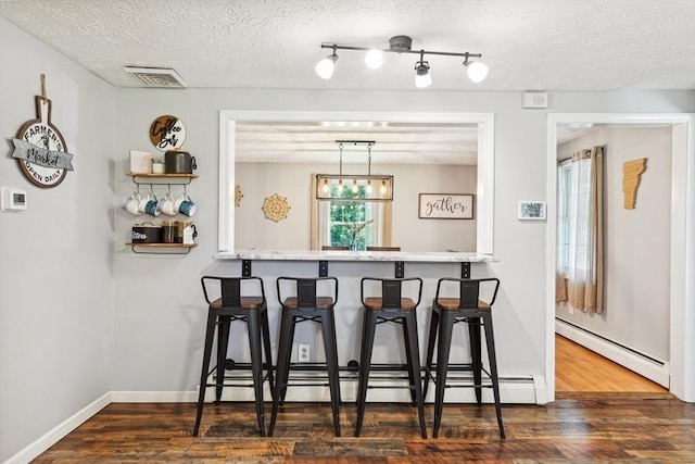 15 Bunny Ln, Brooklyn, CT 06234 - kitchen featuring a baseboard heating unit, wood finished floors, a kitchen bar, a textured ceiling, and a baseboard radiator