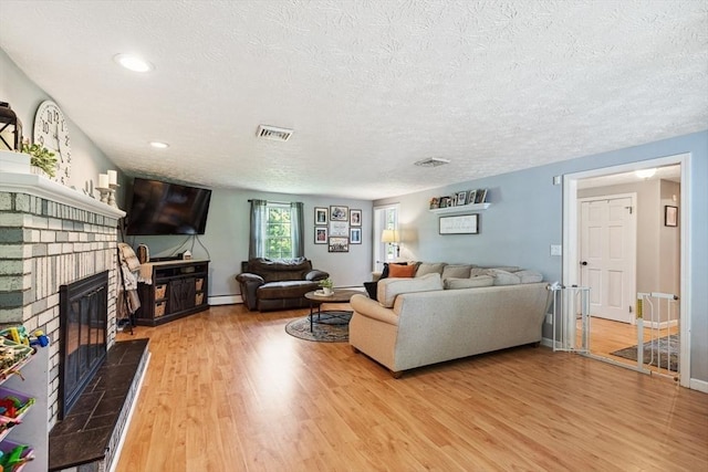 15 Bunny Ln, Brooklyn, CT 06234 - living area featuring light wood-style floors, a textured ceiling, a fireplace, a baseboard heating unit, and baseboards