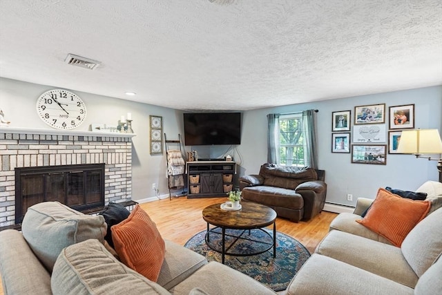 15 Bunny Ln, Brooklyn, CT 06234 - living room with a brick fireplace, a baseboard heating unit, wood finished floors, a textured ceiling, and baseboards
