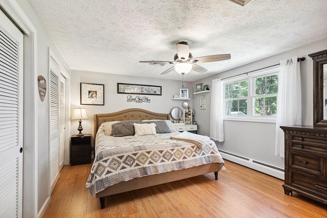 15 Bunny Ln, Brooklyn, CT 06234 - bedroom with a baseboard heating unit, light wood-style floors, ceiling fan, a textured ceiling, and multiple closets