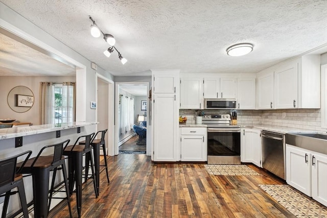 15 Bunny Ln, Brooklyn, CT 06234 - kitchen featuring appliances with stainless steel finishes, a kitchen breakfast bar, white cabinets, dark wood-type flooring, and decorative backsplash