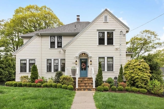 view of front of house with a front lawn, a chimney, and a shingled roof