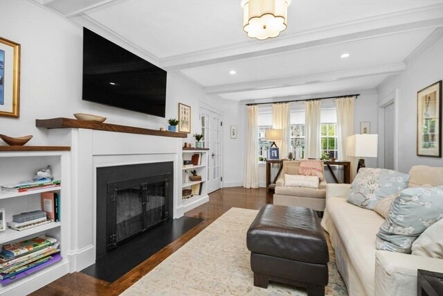 living area featuring wood finished floors, a fireplace with flush hearth, beamed ceiling, recessed lighting, and ornamental molding