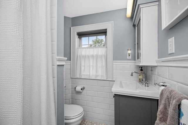 full bath with tile walls, wainscoting, toilet, and vanity