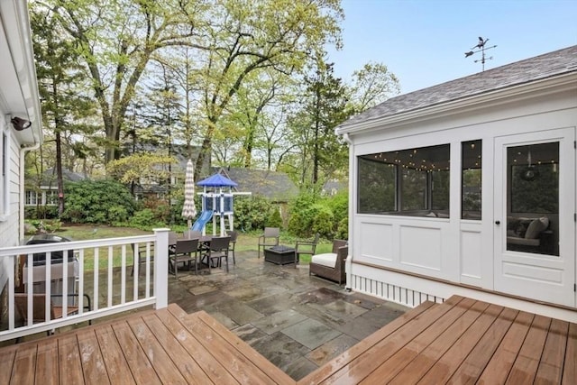 wooden terrace with a patio area, a playground, and outdoor dining space