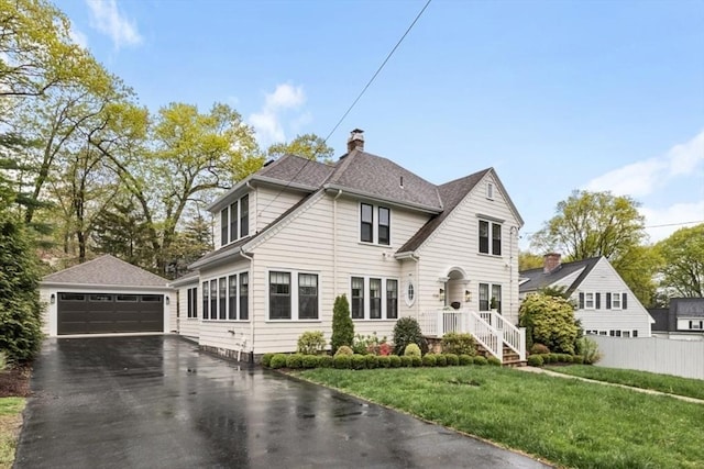 view of front of house featuring an outbuilding, a detached garage, and a chimney