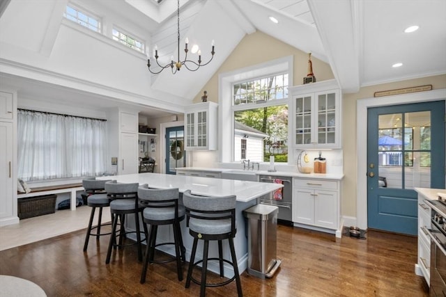 kitchen featuring stainless steel appliances, light countertops, high vaulted ceiling, a breakfast bar area, and a sink