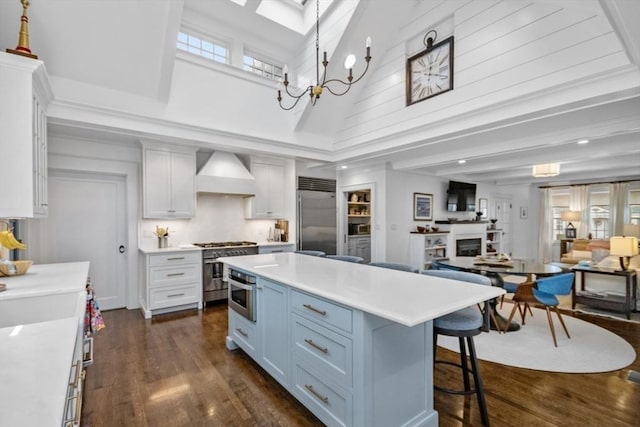 kitchen featuring high end appliances, custom exhaust hood, a towering ceiling, dark wood-style floors, and light countertops