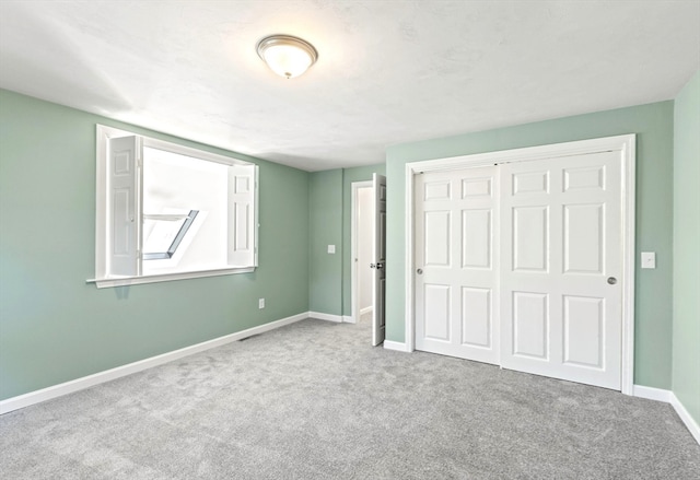 unfurnished bedroom featuring a skylight, light carpet, and a closet