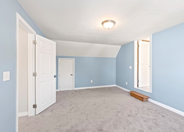 additional living space featuring lofted ceiling and light carpet