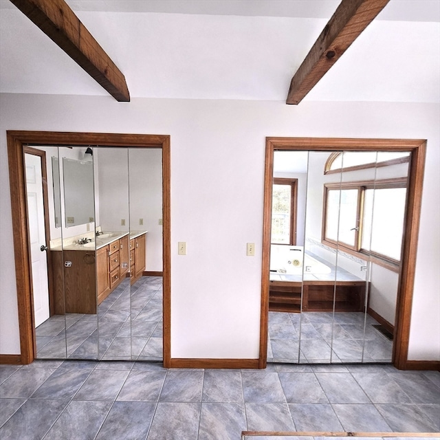 unfurnished bedroom with dark tile patterned floors, beamed ceiling, and a closet