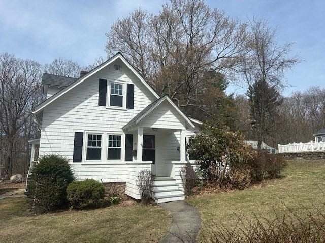 bungalow with covered porch, a front yard, and a chimney